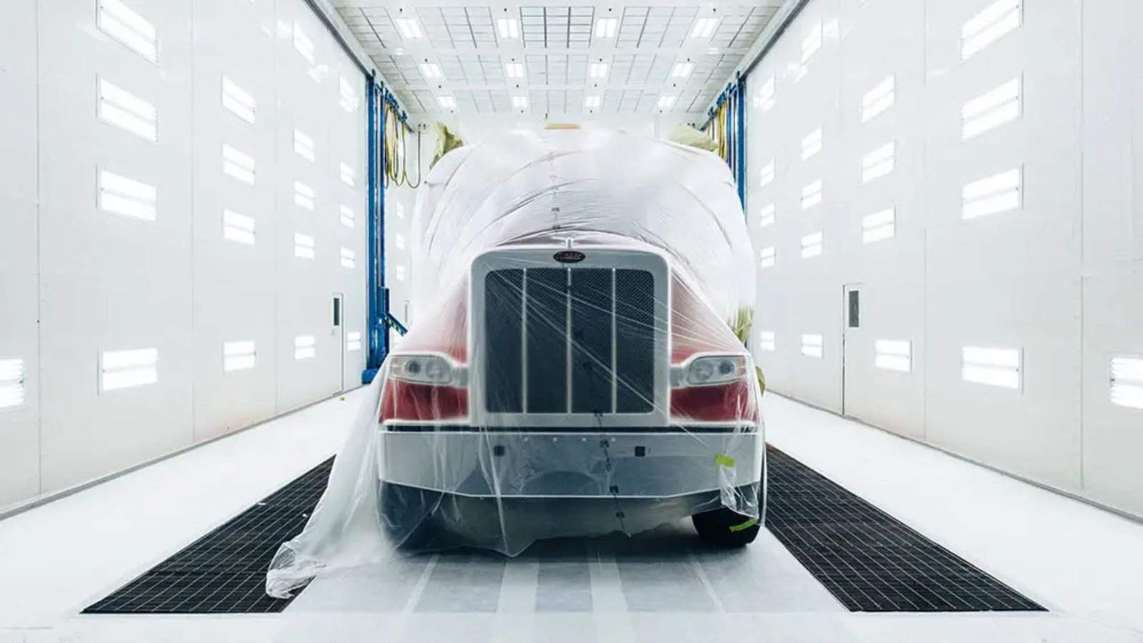 Clean, organized commercial paint shop floor with a truck staged in a paint booth