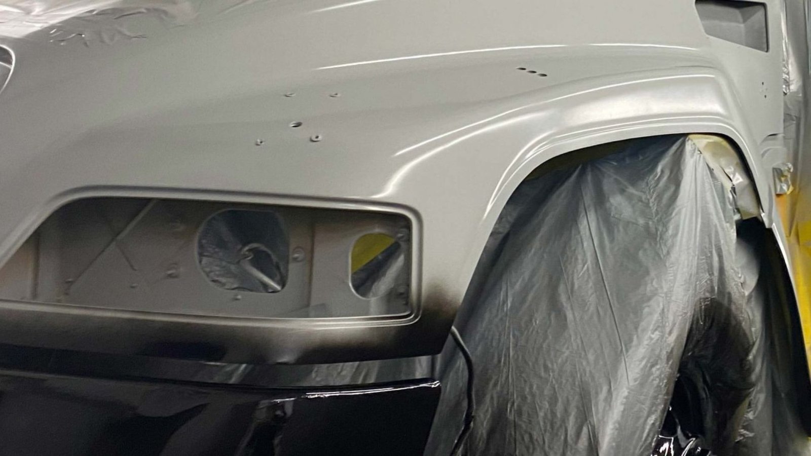 Technician sanding and preparing a truck body panel for refinishing